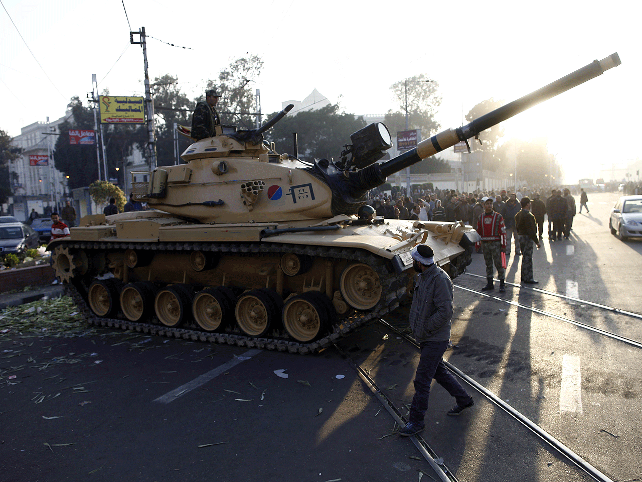 Egyptians walk past army tanks deployed near the presidential palace in Cairo after five demonstrators died overnight in clashes between supporters and opponents of Islamist President Mohamed Morsi on December 6, 2012.  