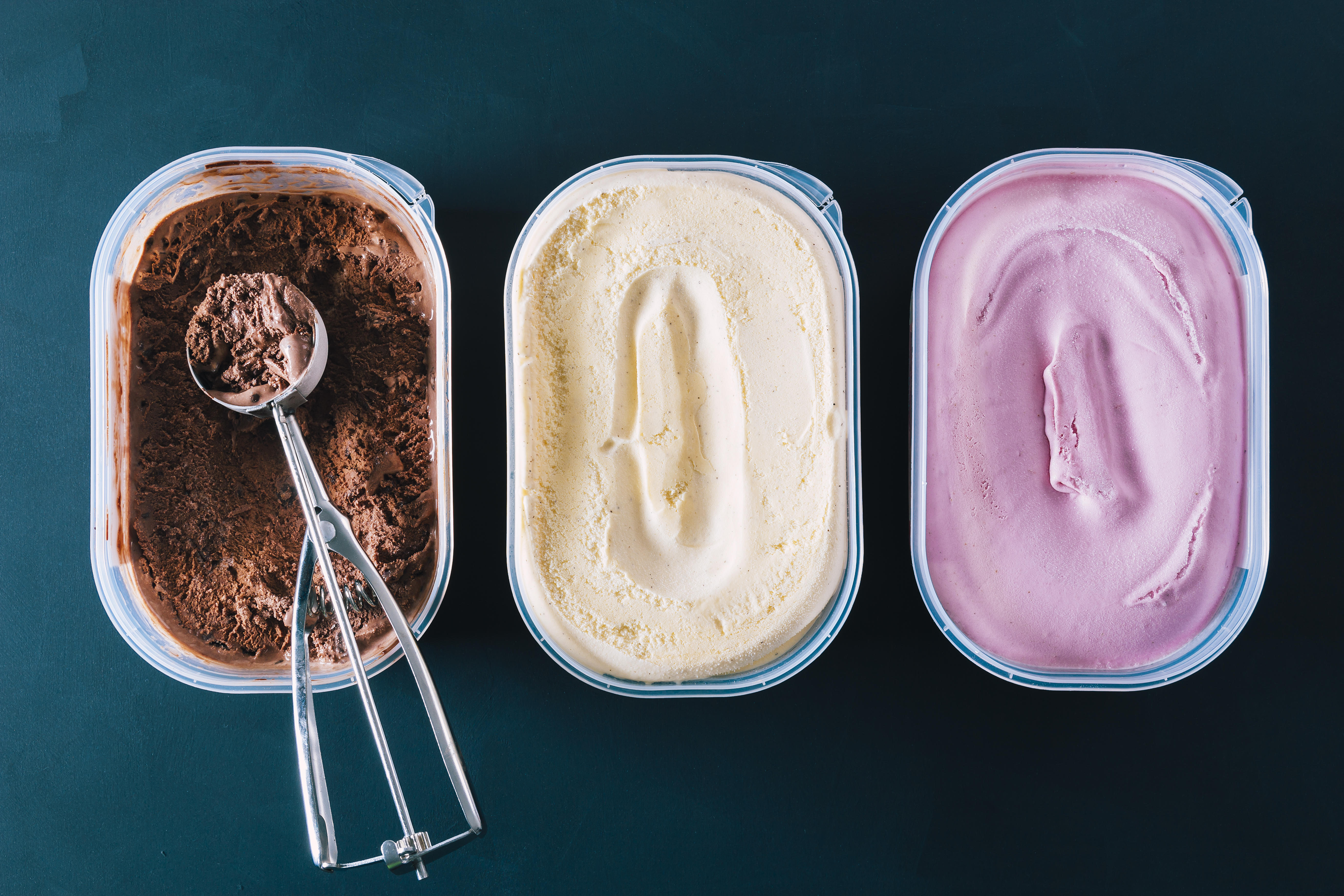 Chocolate, vanilla and strawberry ice cream tubs with scoop 