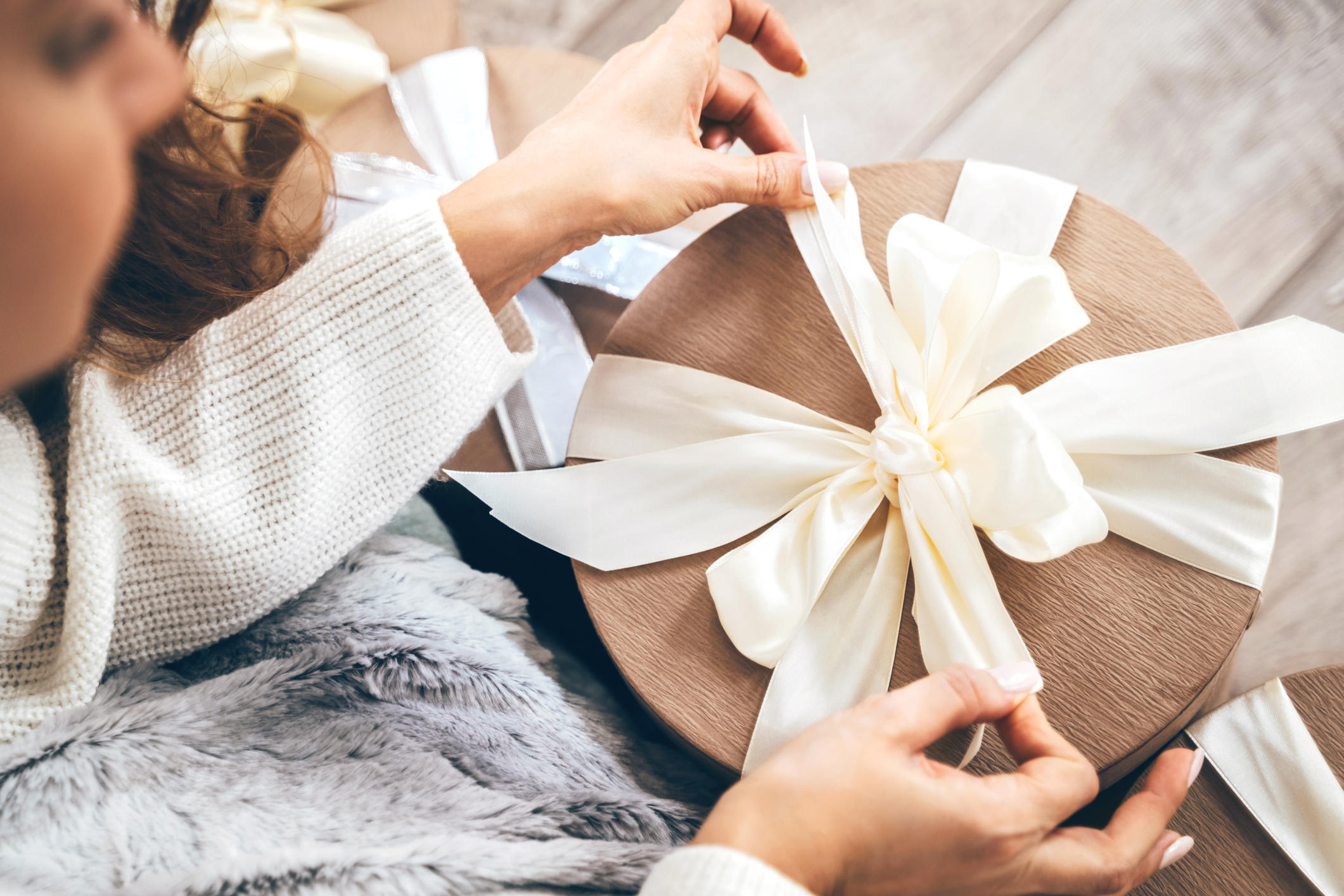 Close-up of a woman wrapping gifts and tying a beautiful pastel ribbon bow 