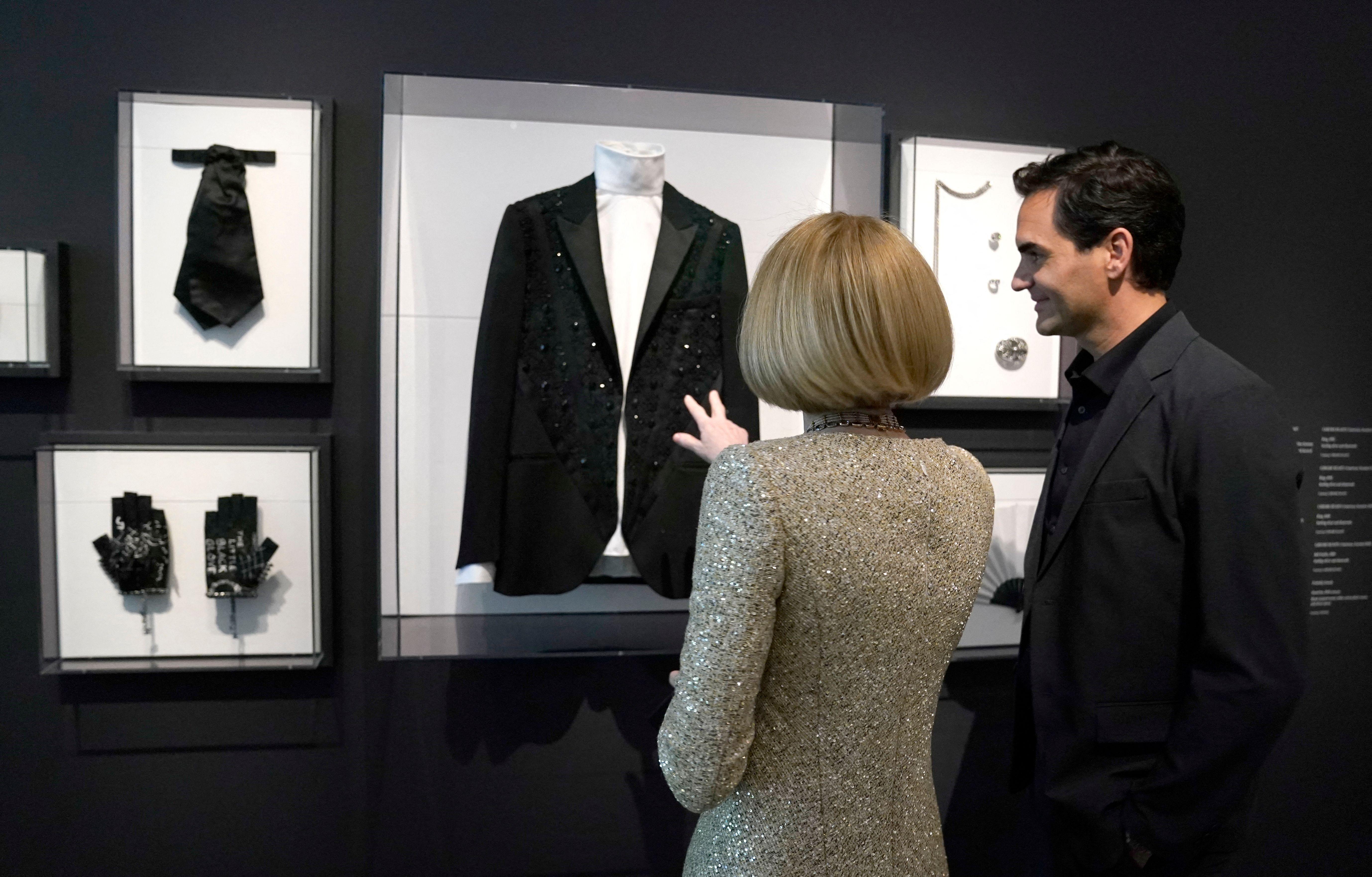 Anna Wintour and Roger Federer looking at item belonging to Karl Lagerfeld. 