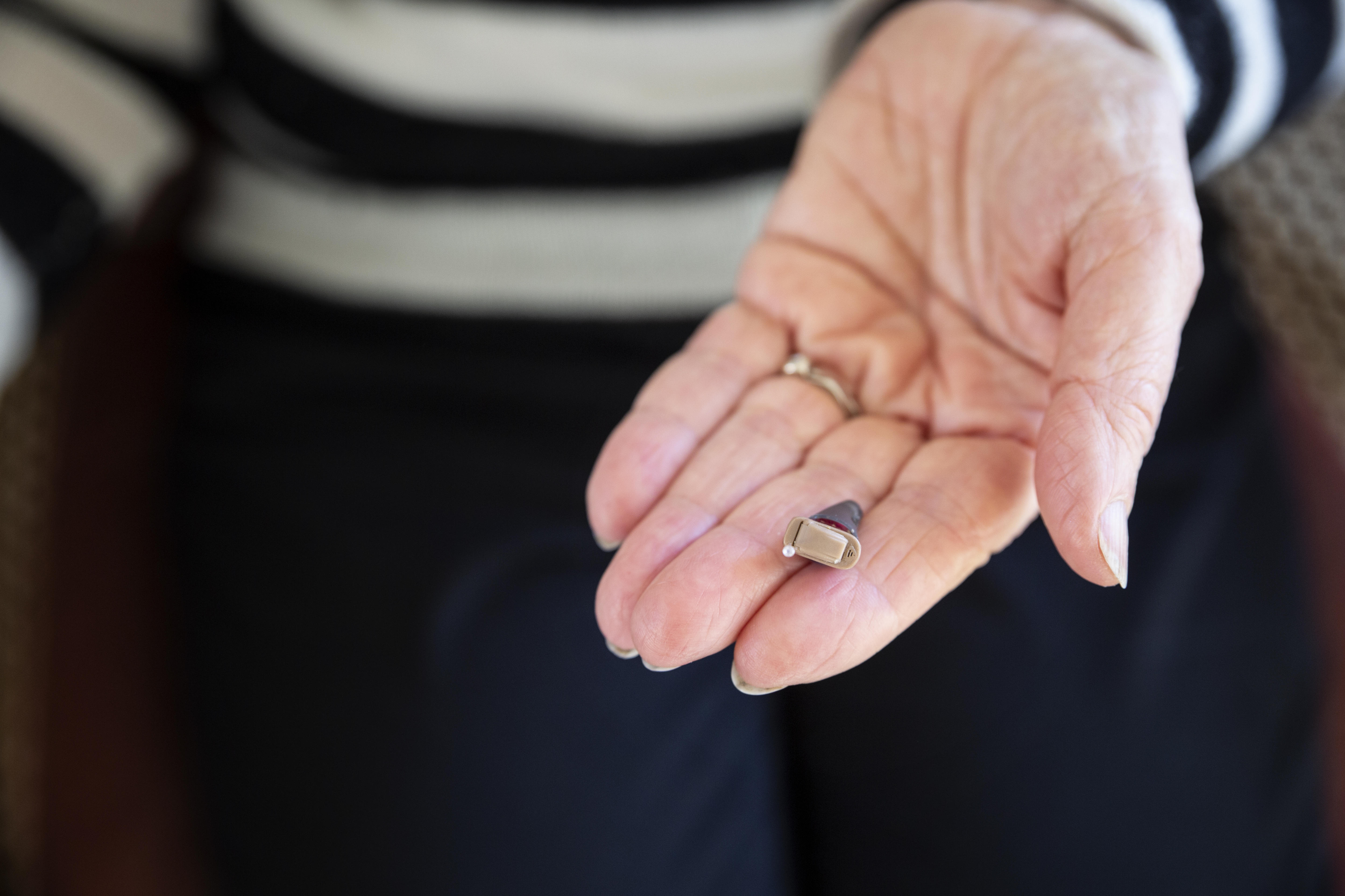Senior woman's hand with modern hearing aid 