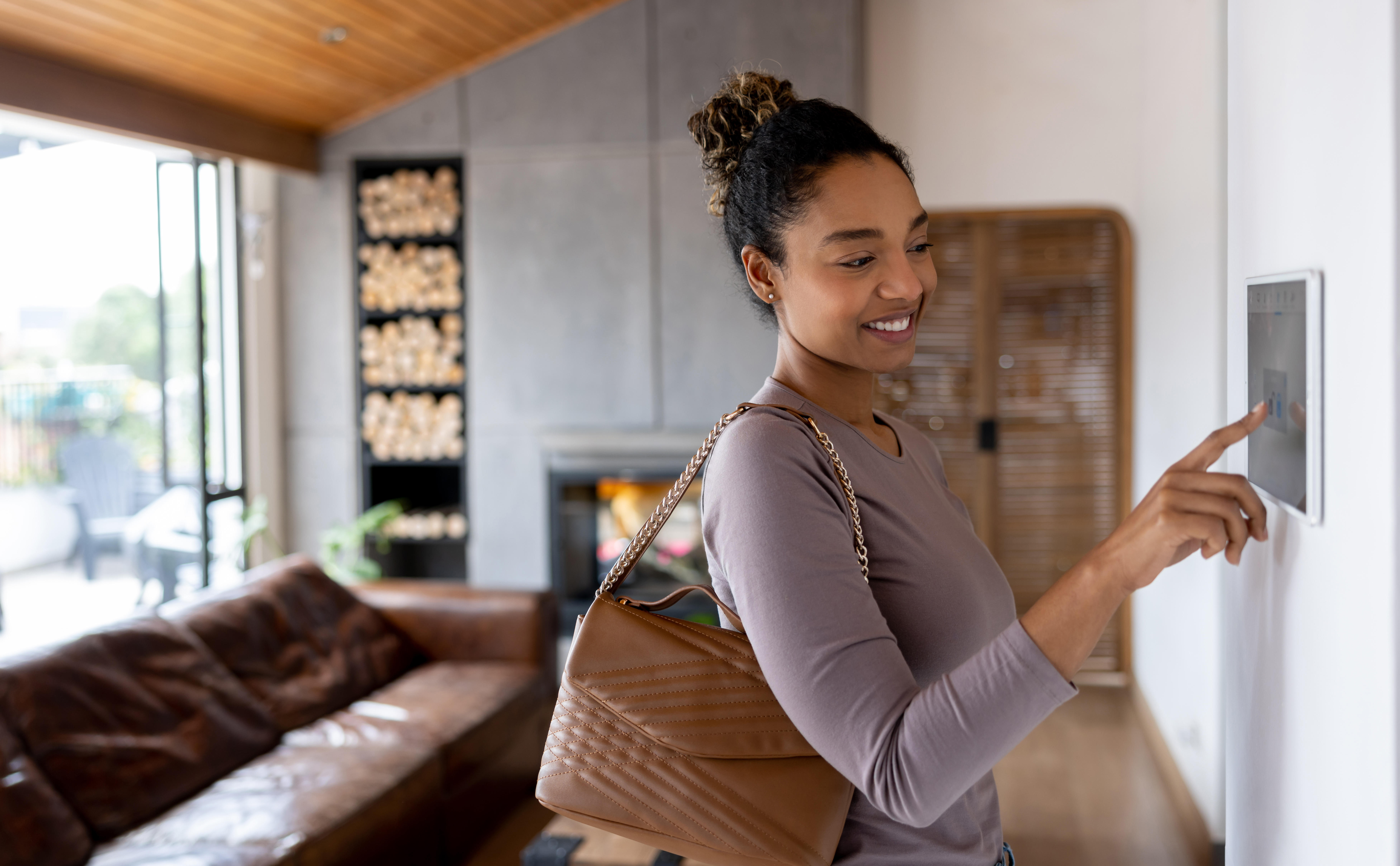Woman activating the alarm while leaving her smart home 