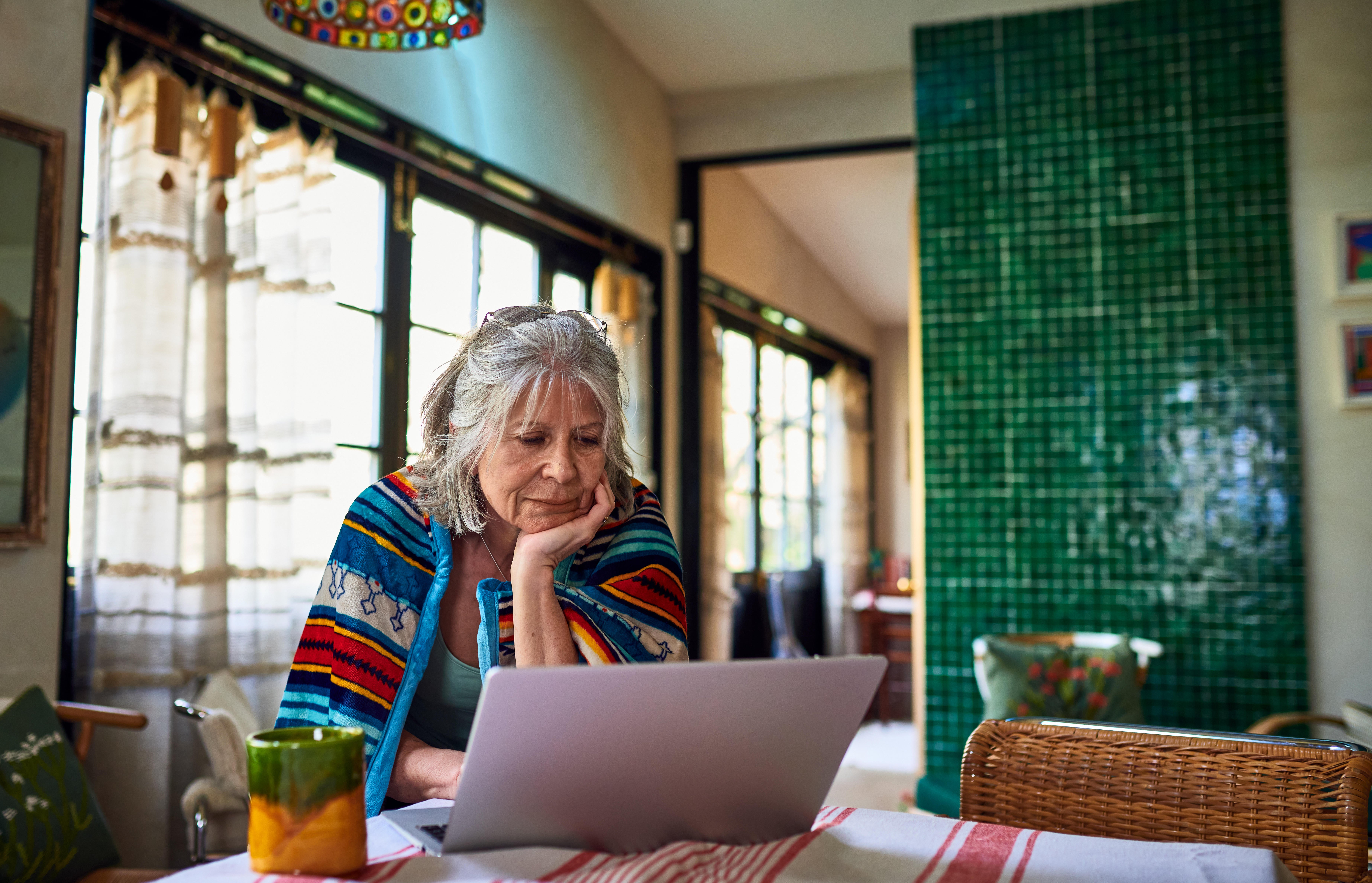 Grey haired woman working from home using laptop