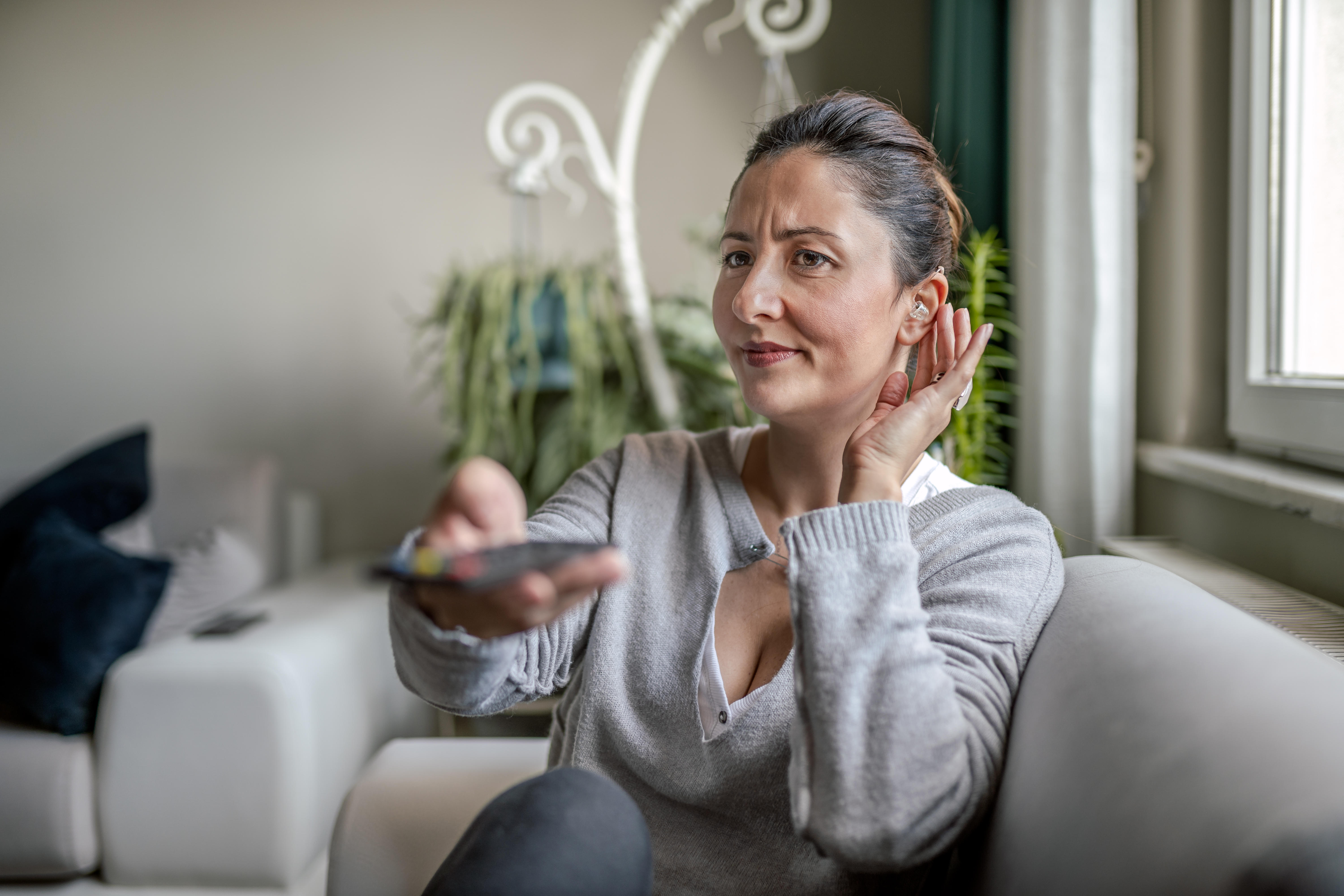 Young Adult Woman with Hearing Aid watching television 