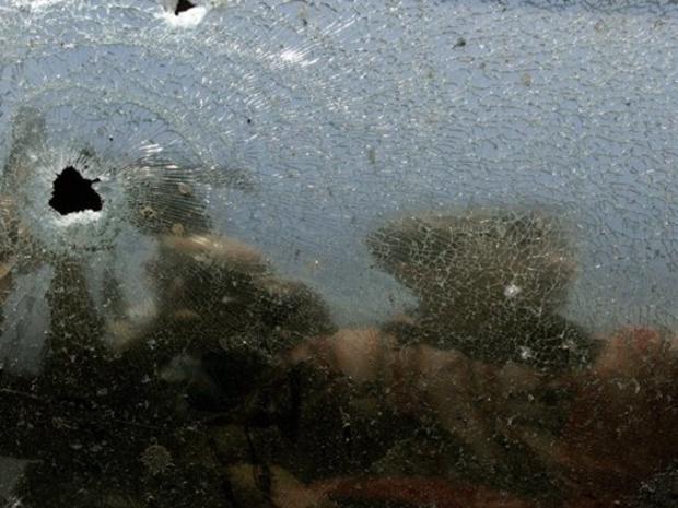 Iraqi soldier is reflected on broken car shield glass 