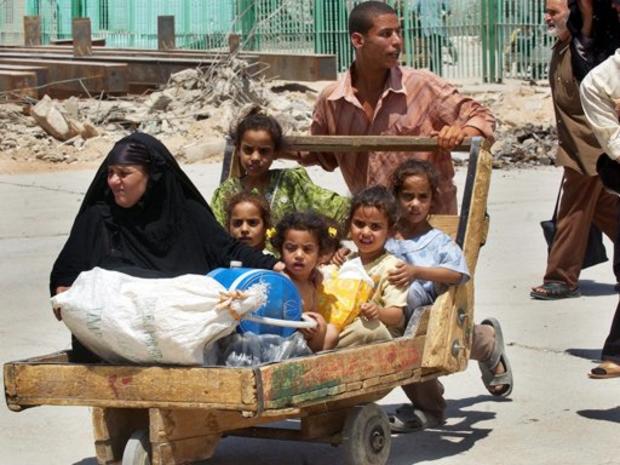 An Iraqi woman and children are pushed in a wooden cart 