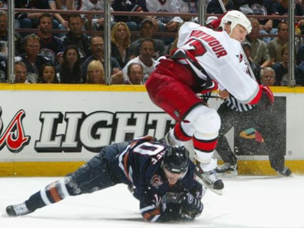 Rod Brind'Amour #17 of the Carolina Hurricanes lays a body check on Shawn Horcoff 