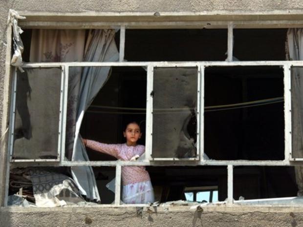 Iraqi girl looks out through the shattered windows 