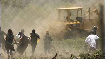 Supporters of the South Central Urban Garden rush after a bulldozer to stop it from destroying land 