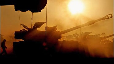 An Israeli soldier runs to reload an Israeli mobile artillery piece after it fired towards the Gaza Strip from a position near Kibbutz Nahal Oz 