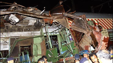 Police and onlookers stand around the mangled compartment of one of the blast affected local trains in Mumbai 