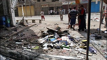 Local Iraqis gather around the site of a suicide bomber's attack 