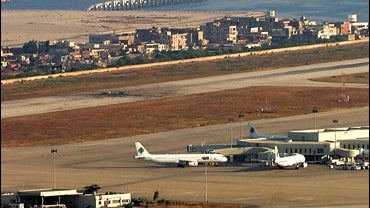 A crater is seen next to planes on a runway after Israeli warplanes targeted the Rafik Hariri International Airport 