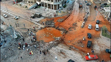 Citizens gather around a crater after Israeli airstrikes 