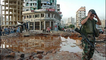 Lebanese soldier stands next to a crater following Israeli airstrikes 
