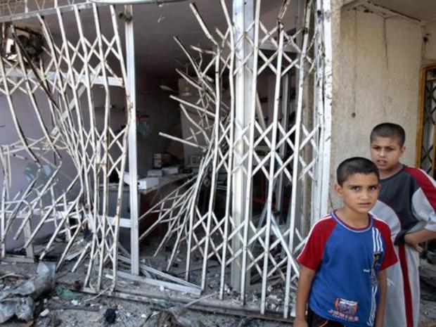Iraqi boys pose in front of the entrance of a shop ruined by a bomb explosion in Baghdad, July 19, 2006. 