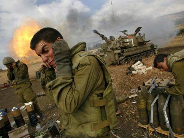 Israeli soldiers cover their ears as an artillery unit fires shells towards southern Lebanon 