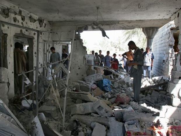 Local residents stand in the rubble of a home hit by a U.S. airstrike during a raid 