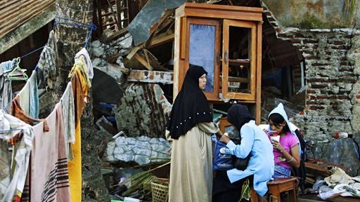 An Indonesian family sits outside of their tsunami ravaged house Friday July 21, 2006 in Pangandaran, Indonesia. 