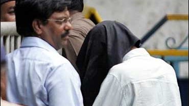 Police officers escort Tanvir Ahmed Mohammed Ansari, 33, right, to a lockup in Bombay, India, 
