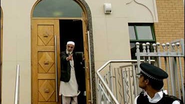British police officer looks around as a man gestures at members of the media outside a mosque in northeast London, Friday Aug. 11, 2006. 