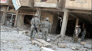 U.S. soldiers inspect the damage, after Sunday night rocket attacks on a residential building, in Baghdad 