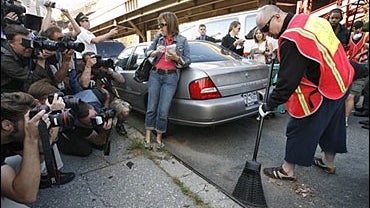 Boy George, right, who was born George O'Dowd, is photographed by the press as he sweeps a curb 