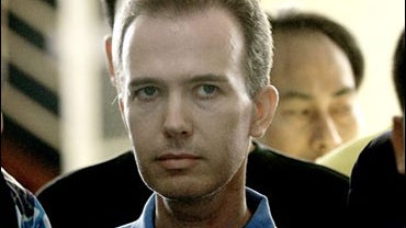 American John Mark Karr, center, is surround by Thai and American officers as he is led out of detention center for a police news conference at Immigration office in Bangkok 