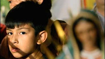 Saul Arellano, 7, stands with is his mother, Elvira Arellano, in front of religious statues as they join community groups for a news conference at Adalberto United Methodist Church in Chicago on Friday, Aug. 18, 2006. 