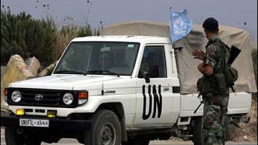 A Lebanese soldier waves to an UNIFIL vehicle driving along the Lebanese-Israeli border August 20, 2006 in the town of Kafarkila. 