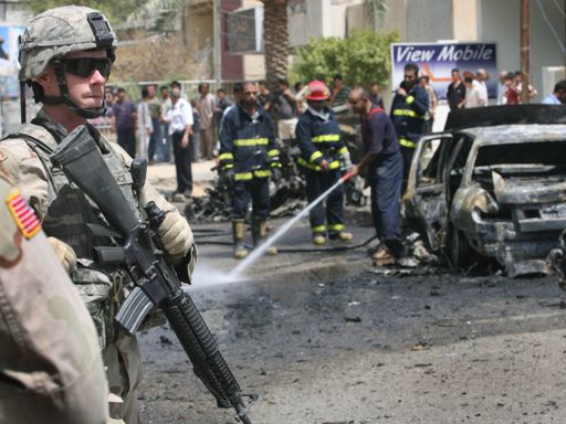 Iraqi policemen question a child at the site of a car bomb explosion, in Baghdad, Iraq 