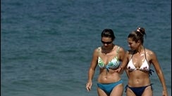 Israeli sunbathers walk on the beach as an Israeli naval boat patrols off the northern Israeli coast next to the border crossing with Lebanon at Rosh Haniqra, northern Israel 