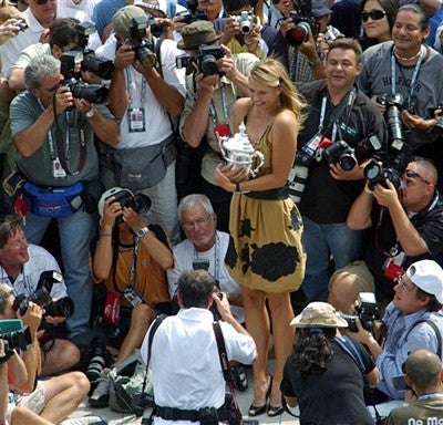 Maria Sharapova, of Russia, the US Open women's singles champion, poses with her trophy and photographers at the US Open tennis tournament 