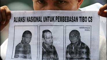 protester holding poster of three Christian militiamen 