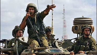 Israeli soldiers sit atop a tracked engineering vehicle as they take positions inside Lebanon near the southern city of Marwaheen, Lebanon, 