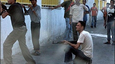 Palestinian gunmen loyal to Fatah take position during an exchange of fire with Hamas security forces during the funeral of Mohammed Mehsen, who was killed during clashes Sunday, at Shifa Hospital in Gaza City 
