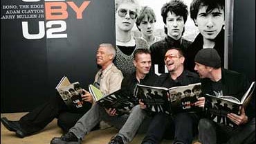 Members of Irish rock band U2, from left, Adam Clayton, Larry Mullen Jr., Bono and The Edge pose in front of a large archive photo of themselves for the media during their book "U2 by U2" signing session at a bookstore in London, Friday, Sept 22, 2006. (P 
