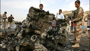 Iraqi soldiers stand around a car bomb wreck at Baghdad's Mustansiriyah Square 