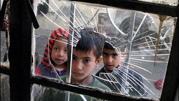 Iraqi boys look through a window that was broken during a raid in Baghdad's Shiite enclave of Sadr City 