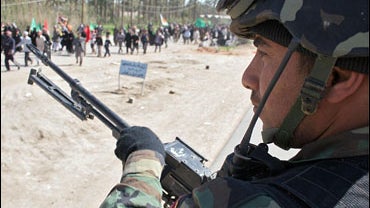 An Iraqi army commando guards Muslim Shiite pilgrims marching towards the shrine city of Karbala, some 100 km south of Baghdad, March 6, 2007. 