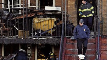 Fire officials investigate the scene of a blaze that claimed the lives of 9 people, including 8 children, in a 4 story apartment building 