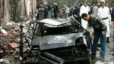 Residents look at the wreckage of a car after a bomb exploded near the prime minister's office in Algiers, Wednesday, April 11, 2007. 