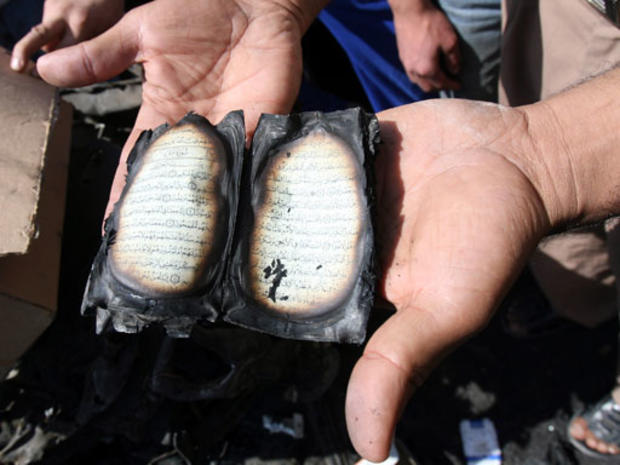 A residents holds a burnt copy of Quran found at the scene of the previous days car bomb attack that killed least 127 people and injured 148 