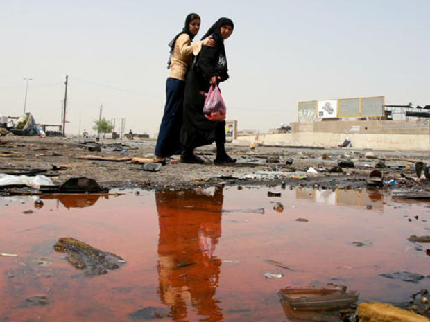 Iraqi woman look at the site of a blast at a bus station in the Baiyaa neighborhood in Baghdad, Iraq, Thursday, June 28, 2007. 