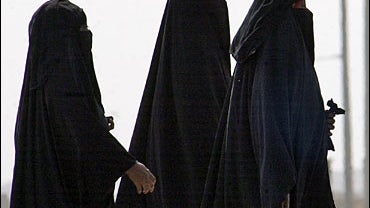 Saudi women walk along a suburban street 