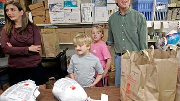 Democratic presidential hopeful, former North Carolina Sen. John Edwards with his children, Cate, from left, Jack, and Emma Claire, package donated food for Thanksgiving during a visit to the Inter-Faith Council and Social Service Food Pantry in Carrboro, 