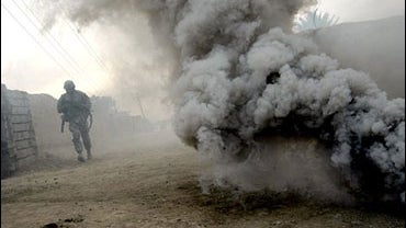 A U.S. army soldier from Ghostrider Company, 3rd Squadron, 2nd Stryker Cavalry Regiment runs through smoke generated by a smoke grenade during Operation Phantom Phoenix in the village of Abu Musa 