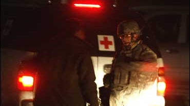 A U.S. soldier chats with an Afghan security man near the Serena Hotel, site of a suicide attack, in Kabul 