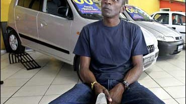 Robson Augusto sits inside the car dealer where he bought his first car in Sao Paulo 