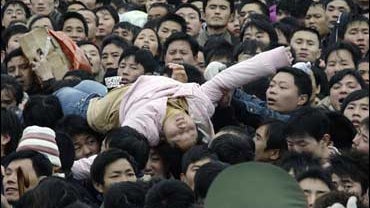A faint passenger is carried away by the crowd as thousands of passengers wait to get inside Guangzhou Railway Station in Guangzhou 